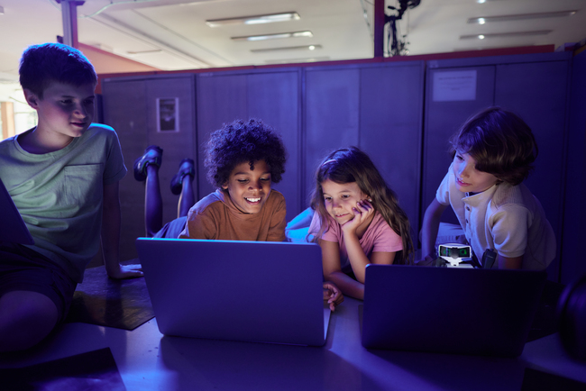 Four elementary school children look at laptops during class Four elementary school children look at laptops during class