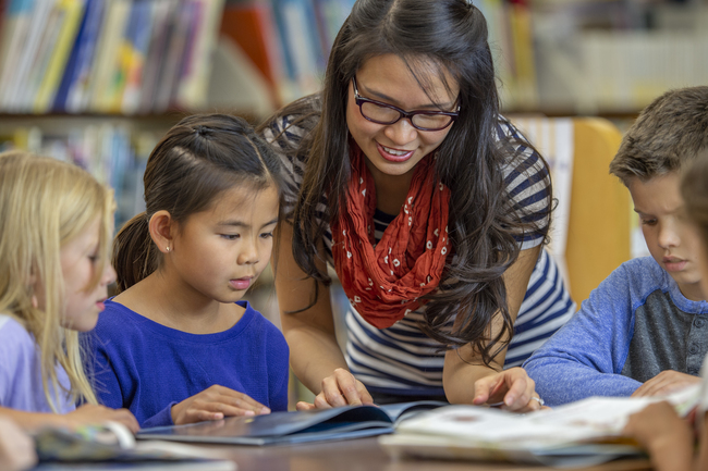 Young teacher instructing a smaller group of elementary students on reading Young teacher instructing a smaller group of elementary students on reading