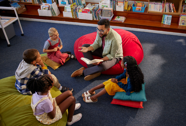 A young teacher reads aloud a picturebook to children