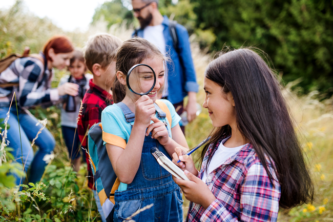 Young elementary students outside exploring with a teacher