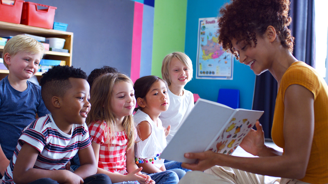 Young teacher reading aloud to her elementary students