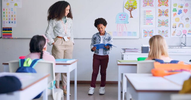 A young teacher with her student at the front of the class presenting