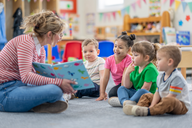 Young teacher reading aloud to preschool students Young teacher reading aloud to preschool students